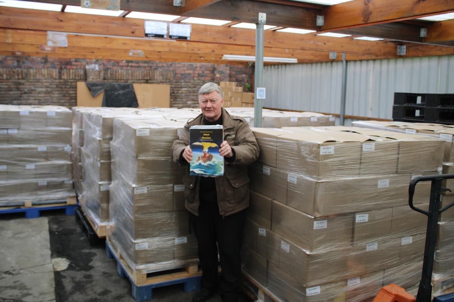 Willem de Vink, schrijver en striptekenaar van Jezus de Messias, bij pallets met boeken