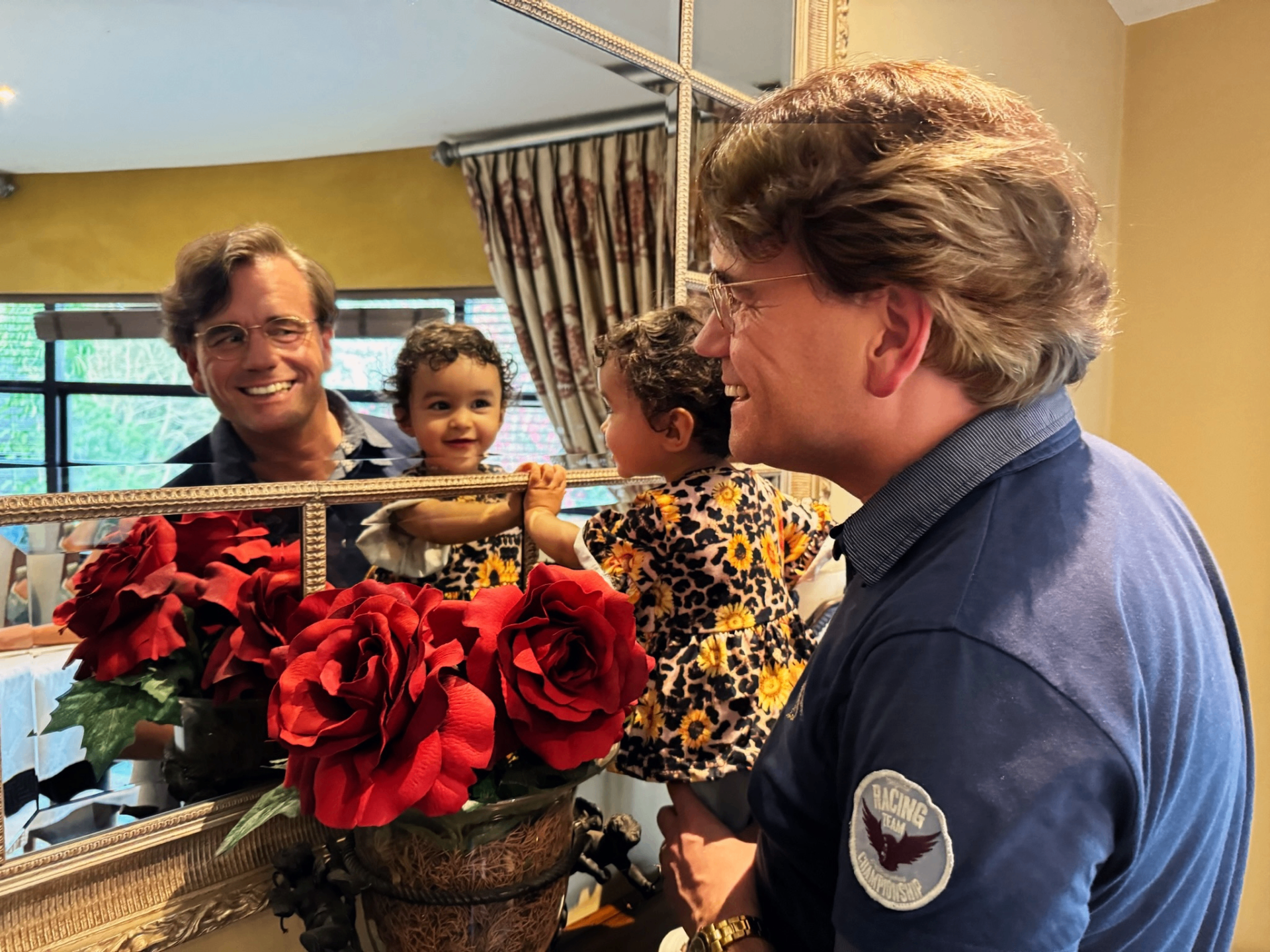 Bas met dochter voor een gouden spiegel met rode rozen — twee gezichten, één liefde.