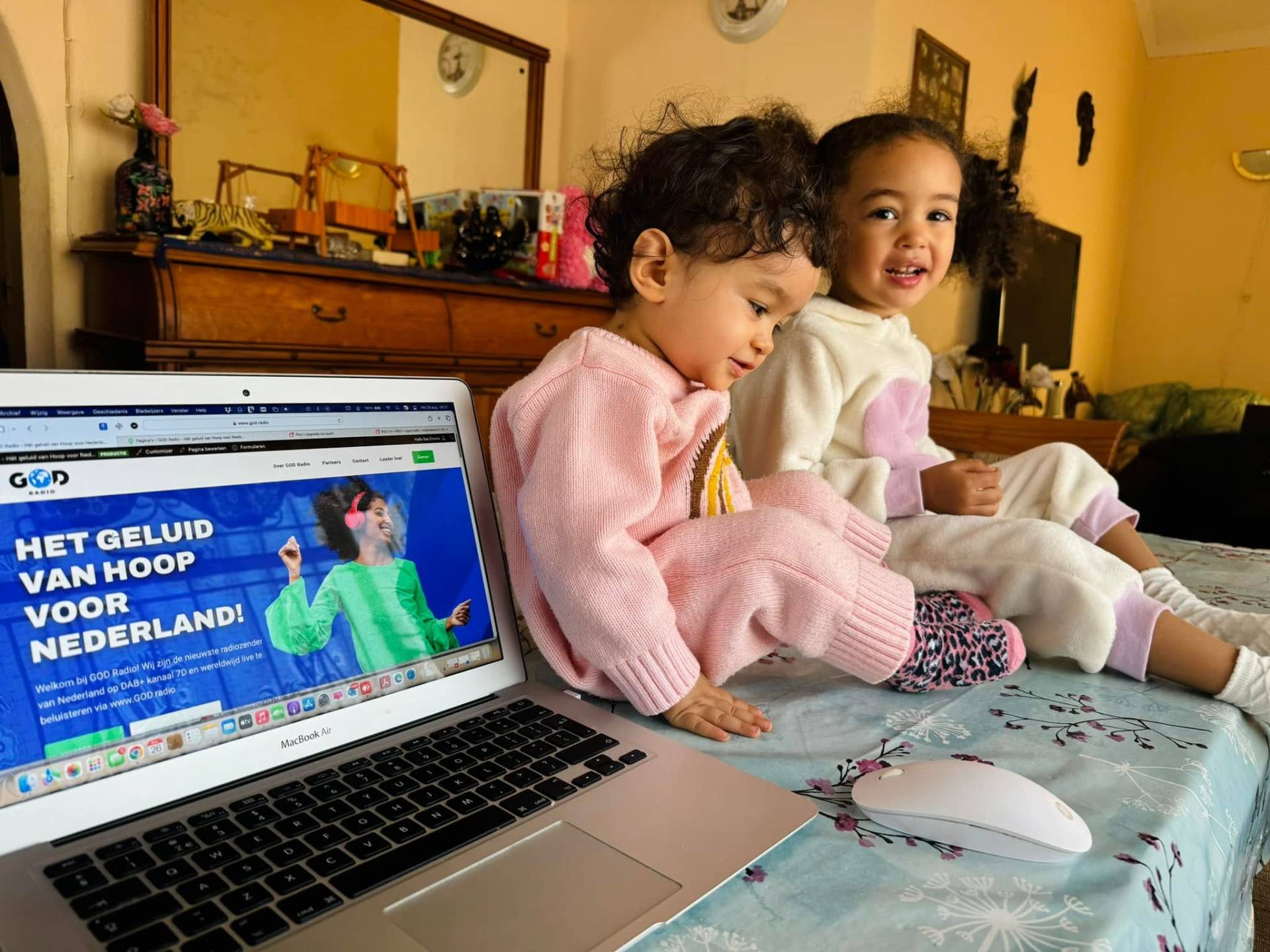 Hope en Faith kijken samen naar GOD Radio op de laptop — de volgende generatie luistert mee.