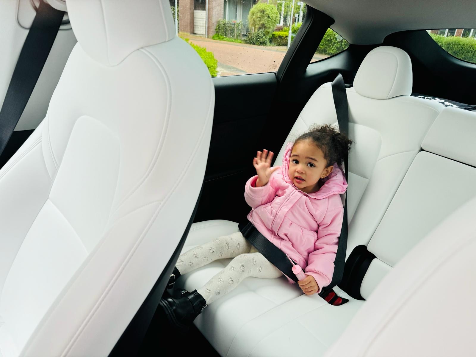 Faith zwaait vanuit de auto — een klein handje, een groot hart.